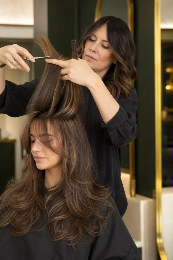 Stylist cutting elevated face framing sections for a modern layered hairstyle